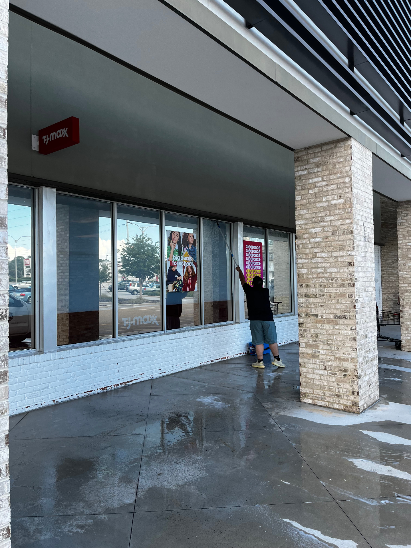 Worker washing storefront windows and awning with an extension wand