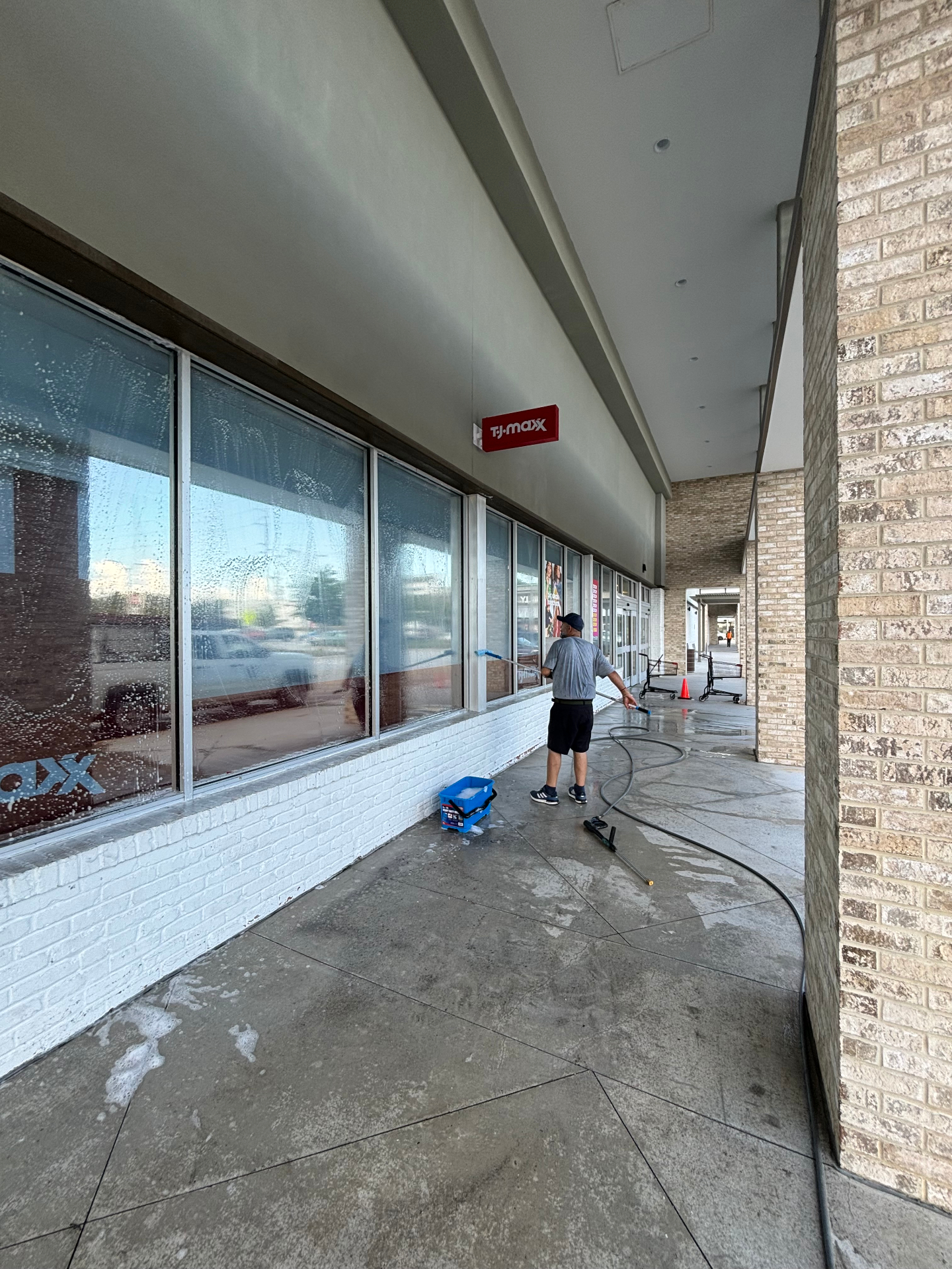 Technician surface cleaning a covered concrete walkway at a shopping center